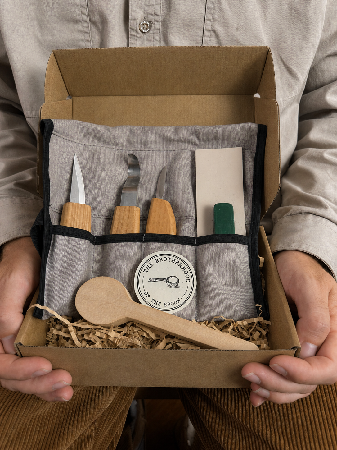 Set of wooden tools in a box held by a person, with 'The Brotherhood of the Spoon' logo.